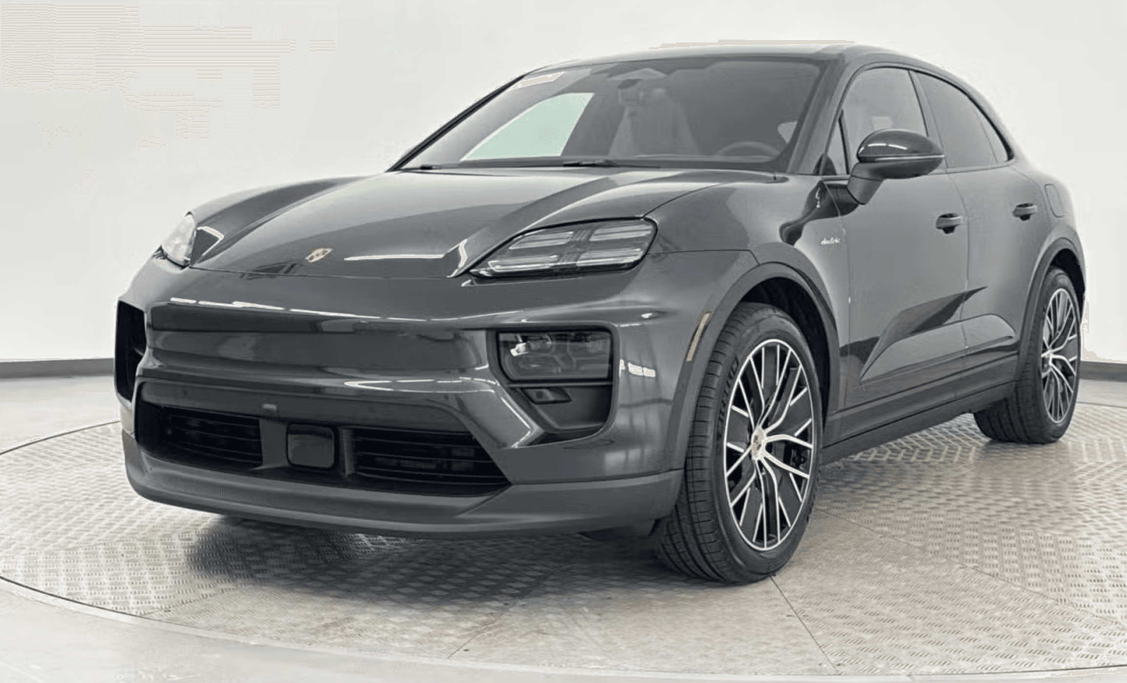 Three-quarter front view of a gray Porsche SUV on a circular showroom turntable. For sale a Porsche Birmingham AL