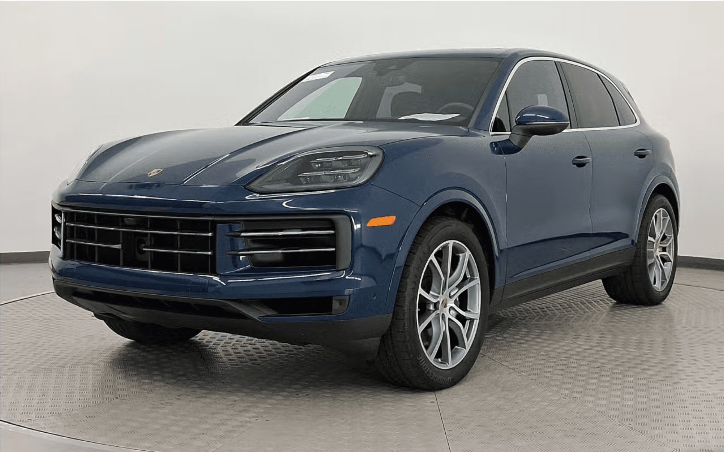 Blue Porsche Cayenne SUV in studio, front three-quarter view showing grille, LED headlights and alloy wheels. Vehicle is for sale a Porsche Birmingham.